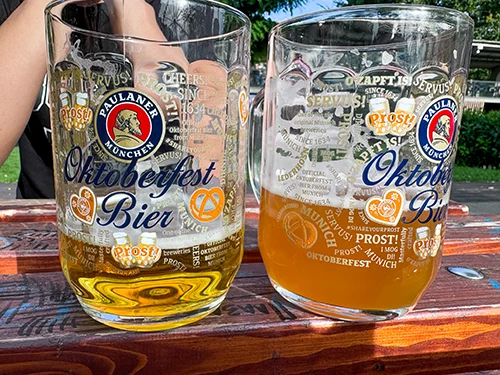 two Oktoberfest beer mugs with some beer in them