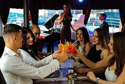 a group of young people toasting with glasses of cocktail on a cruise boat during daytime