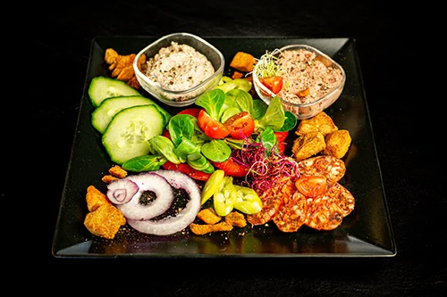 paprika salami slices, red onion, cucumber, pork crackle and spreads on a black square plate