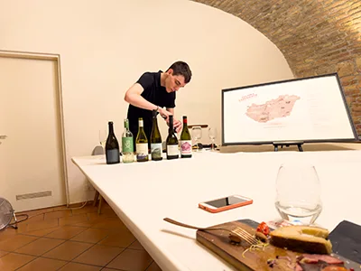 Young male somelier opening a bottle of wine in a vaulted tasting room in Pálinka Museum