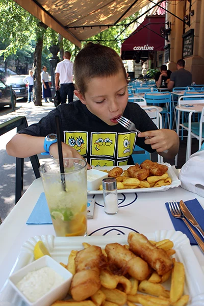 a 10-year old boy eating fish and chips on the terrace of Big Fish Bistro on Andrássy av.