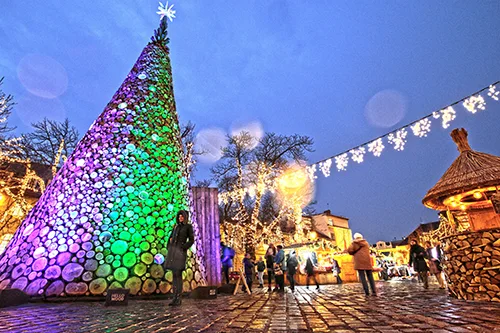 a colourful Christmas tree installation made of logs, in the Main Square of Obuda