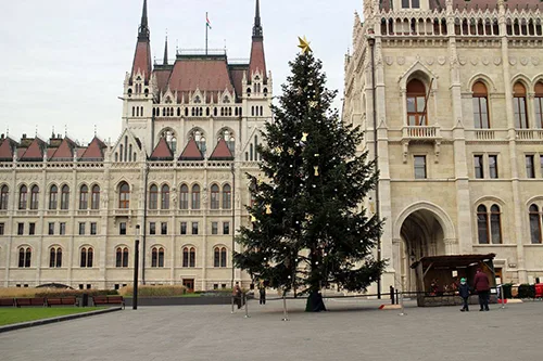 a tall Christmas tree in front of the Parliament in Kossuth Square on a December day