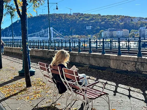 a woman with long blonde hair reading on a bench on the Danube Promenade