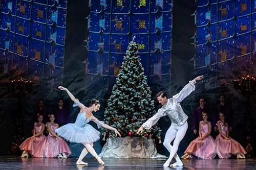 the prima ballerina with her partner performing in the Nutcracker in front of a Christmas tree on the stage of the Hungarian Opera House