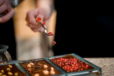 sprinkling dried red fruits onto melted chocolate bars in a mold
