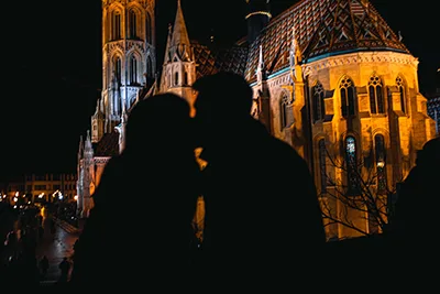 a shadow of a couple kissing in front of Matthias Church in Buda Castle at night