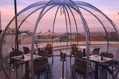 dinner tables inside a see through igloo on the terrace of Aranybastya (the Parliament can be seen in the background at the golden hour)