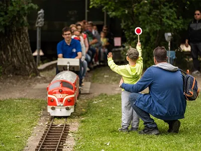 kids and their parents riding on the small garden railway in the Hungarian railway park