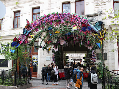 the entrance to the Easter Market in Gozsdu court decorated with pink spring flowers and large butterfly paper maches