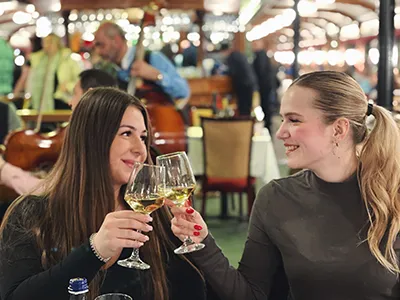 Two young women toasting with a glass of white wine, on an excursion boat
