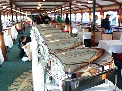 stainless steel containers (covered) on the buffet dinner serving table and a couple of tables set for dinne ron the Count Széchenyi cruise ship on a spring evening