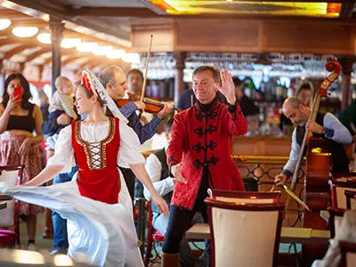 a woman and a man dressed in traditional folk costume dancing on the Szechenyi cruise boat
