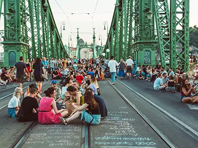 People sitting, walking, drinking wine on the Liberty Bridge