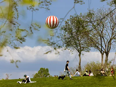 people relaxing on the grass in City park, the red-white striped balloon can be seen up in the air
