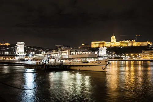 a cruise ship on the Danube near the Chain Bridge at night
